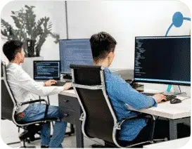 Two QA Experts sitting and writing test automation code on their machines.